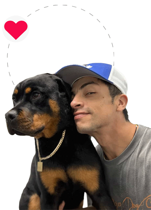 Marc Groomer wearing a blue hat embracing a Rottweiler dog