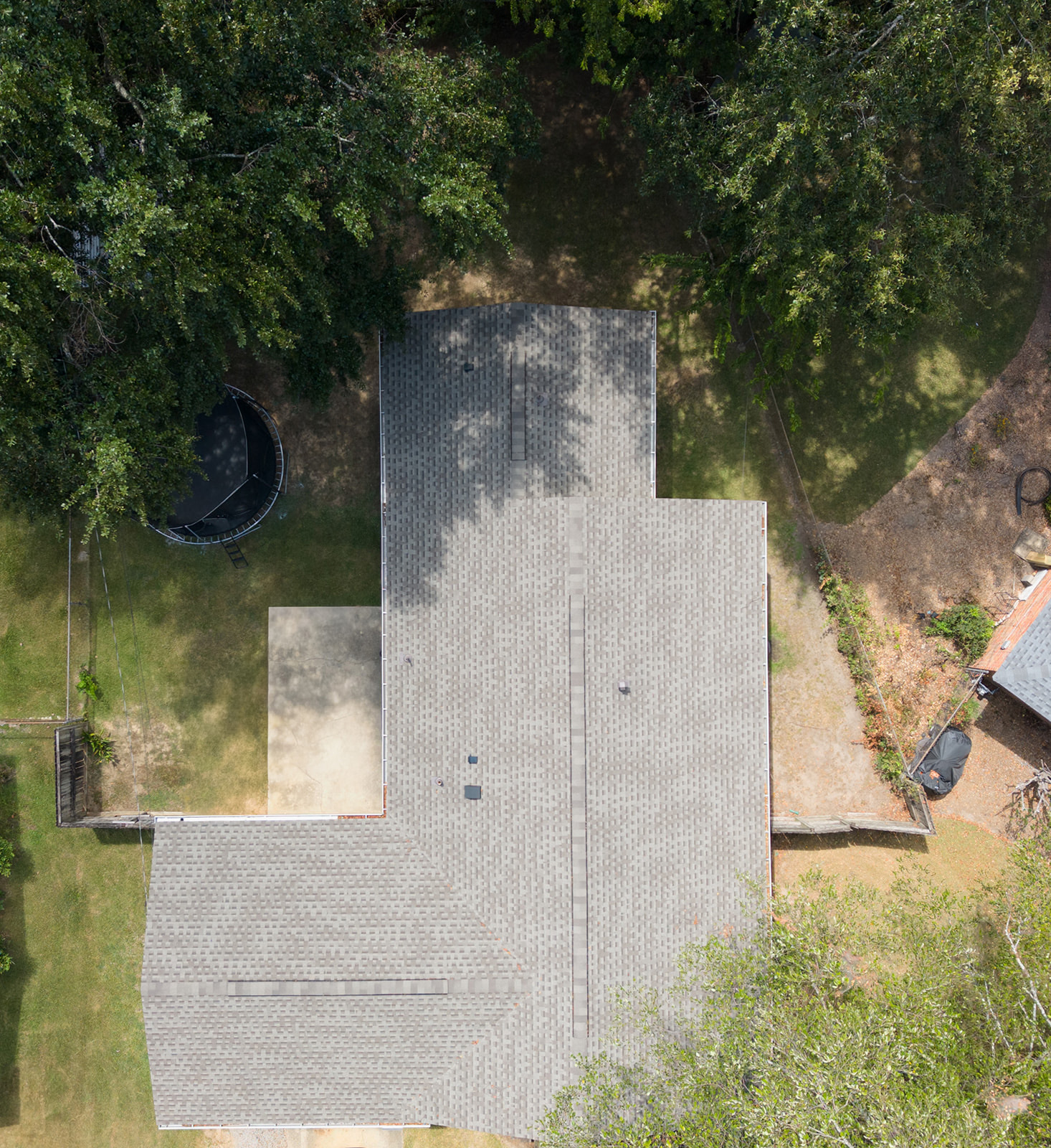 Wooden framework of a house extension under construction next to an existing brick and siding house.