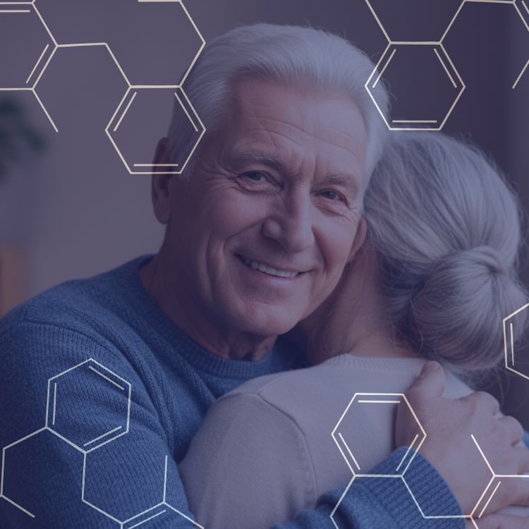 Smiling elderly man hugging a woman with gray hair styled in a bun, overlaid with hexagonal graphic patterns.