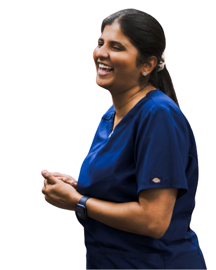 Laughing woman in blue medical scrubs with dark hair tied back and wearing a smartwatch.
