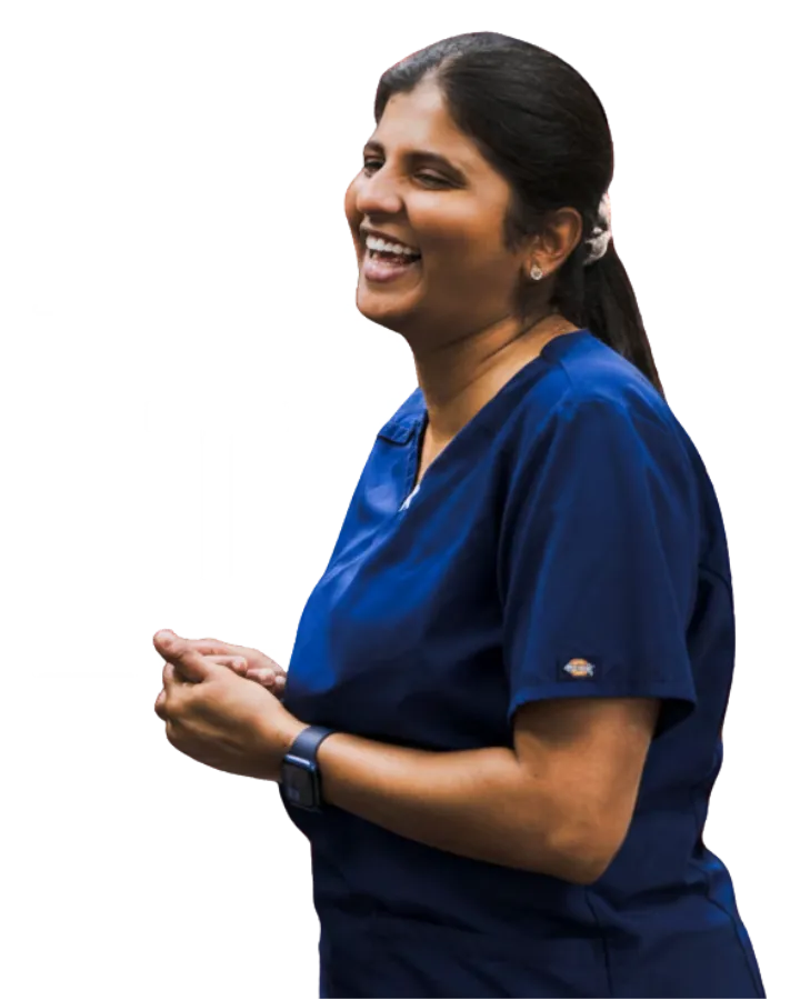 Laughing woman in blue medical scrubs with dark hair tied back and wearing a smartwatch.