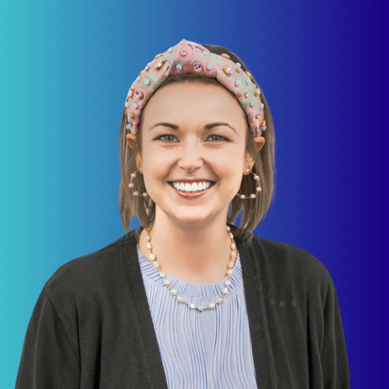 Smiling woman with embellished headband, pearl hoop earrings, and necklace on blue gradient background.