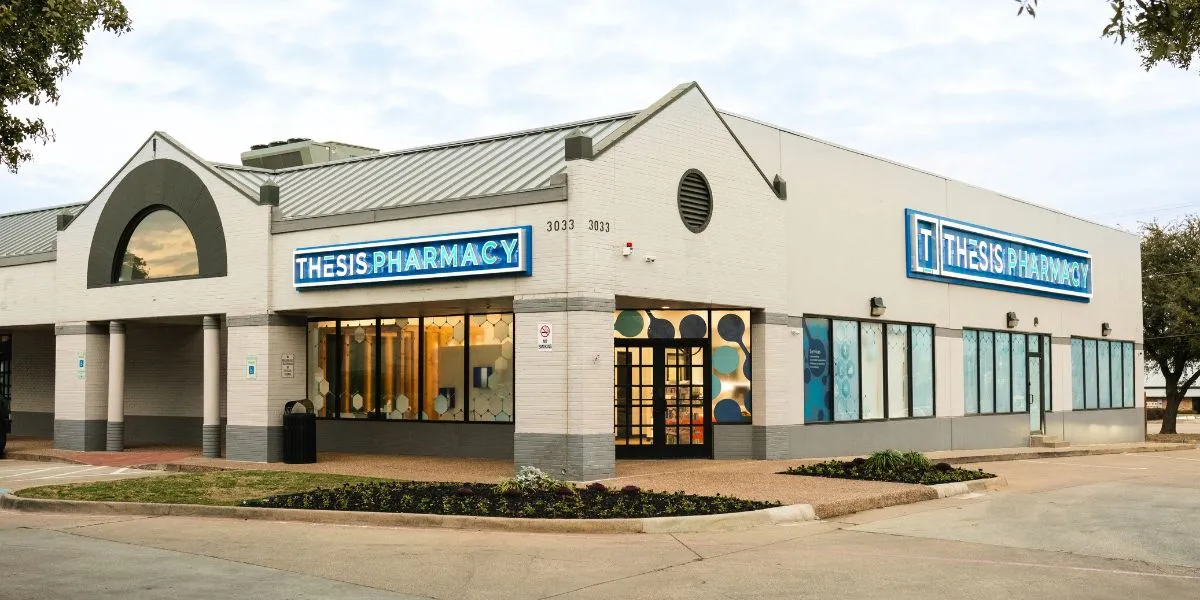 Exterior view of Thesis Pharmacy building with signs and large windows.