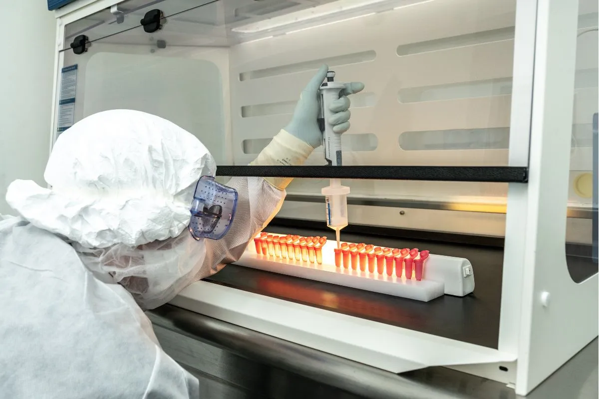 Group of healthcare professionals wearing protective suits, hairnets, masks, and gloves standing in a laboratory.