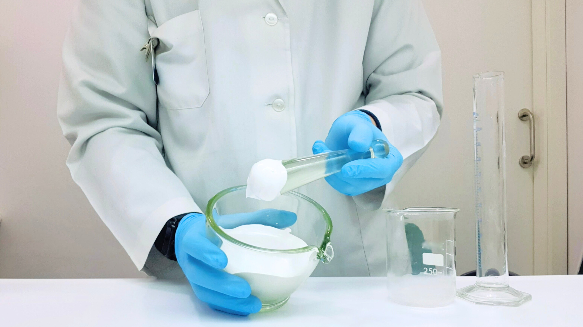 Pharmacist in protective gear dispensing medication in a compounding pharmacy.