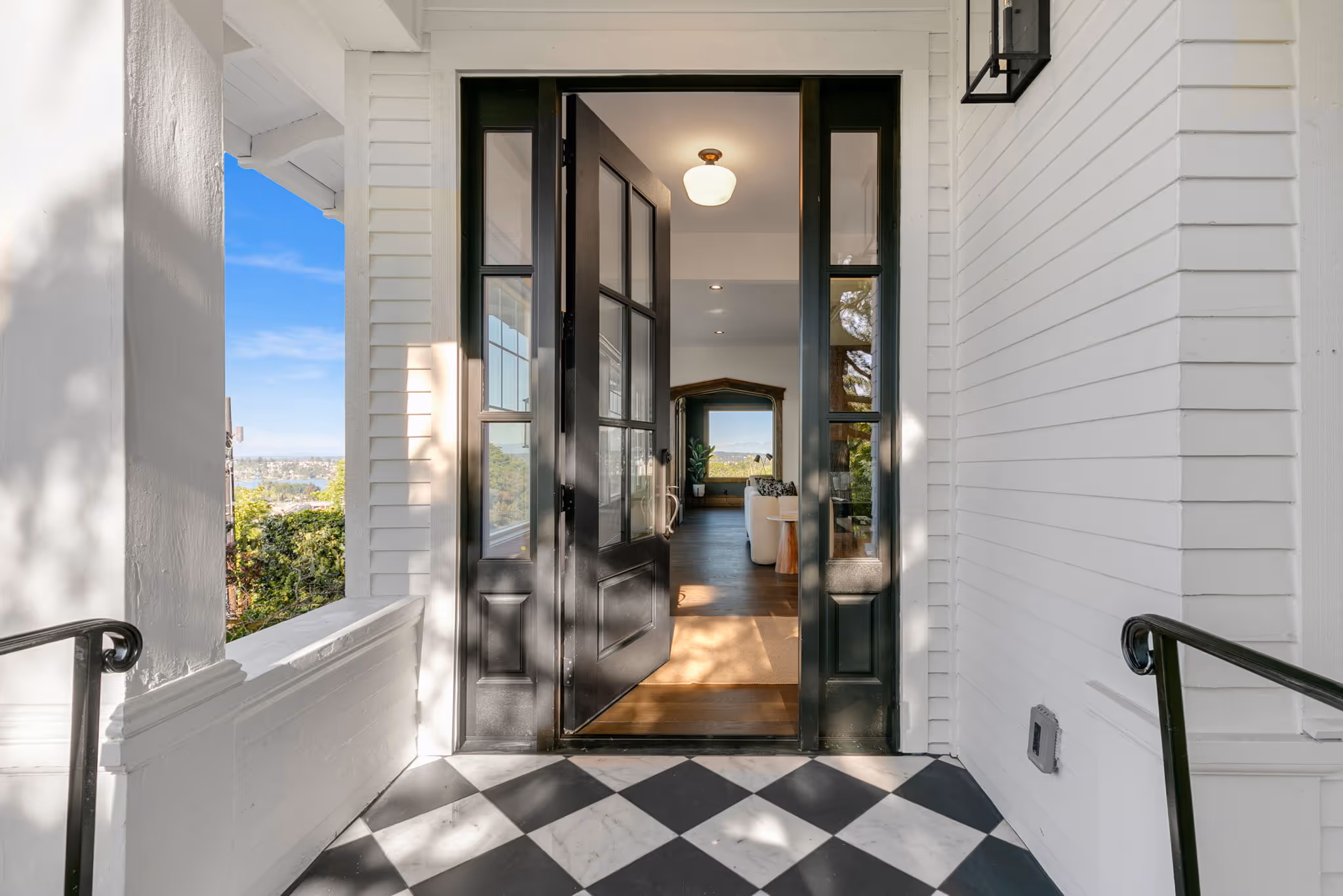 Front entrance with open black framed glass door and black and white checkered floor tiles.