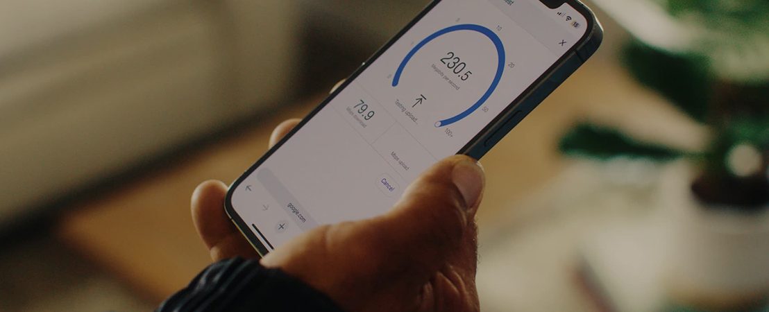 Hand holding smartphone showing internet speed test with 230.5 Mbps download and 79.9 Mbps upload.