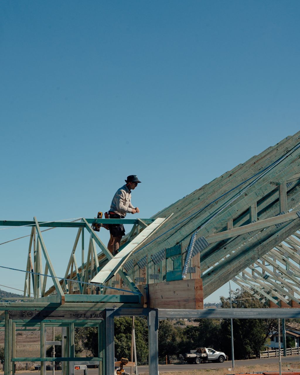 Builder working on timber roof frame during residential construction – The Renew Company sustainable building project.