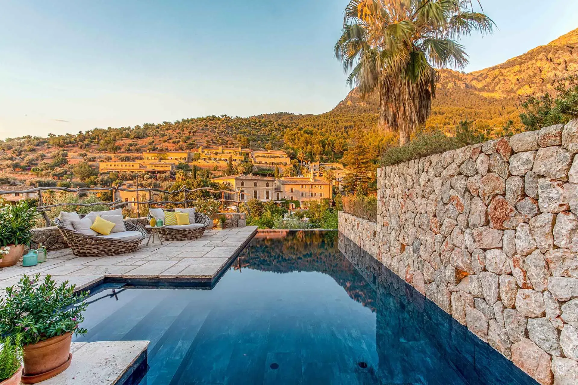 A sleek modern infinity pool at a curated Mallorcan residence, perfectly positioned for sunset views over a historic hillside village.