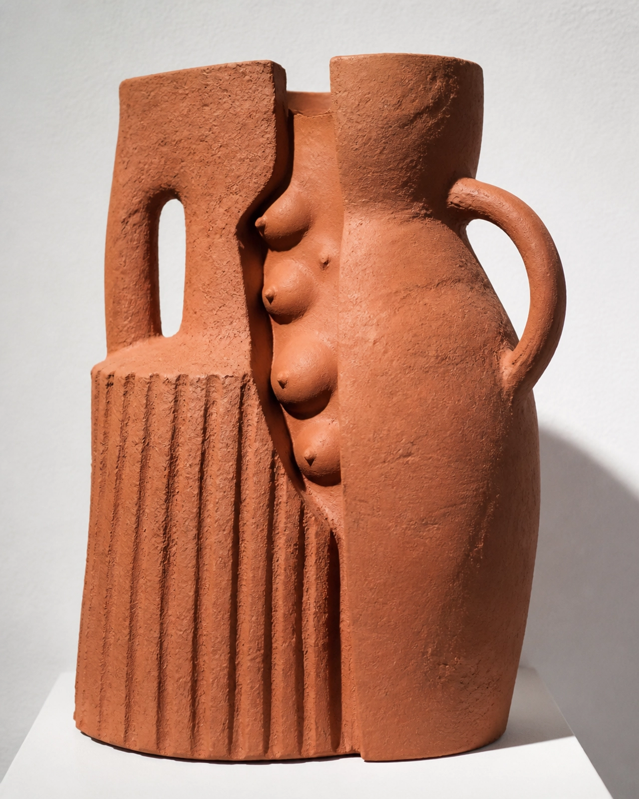 A close-up of a contemporary ceramic sculpture using raw red clay.