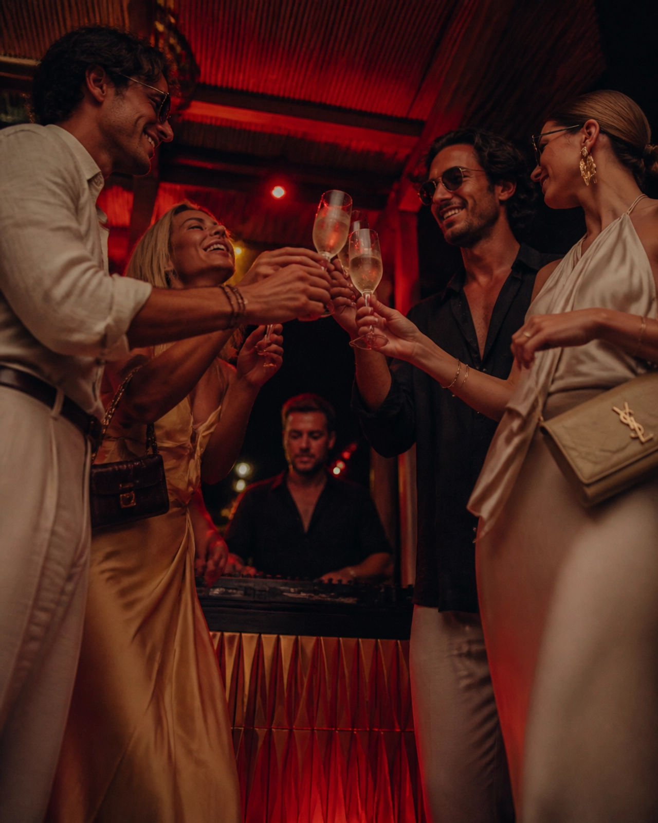 A group of sophisticated travelers at an exclusive summer party in Mallorca, dressed in Italian Summer attire and enjoying prosecco.