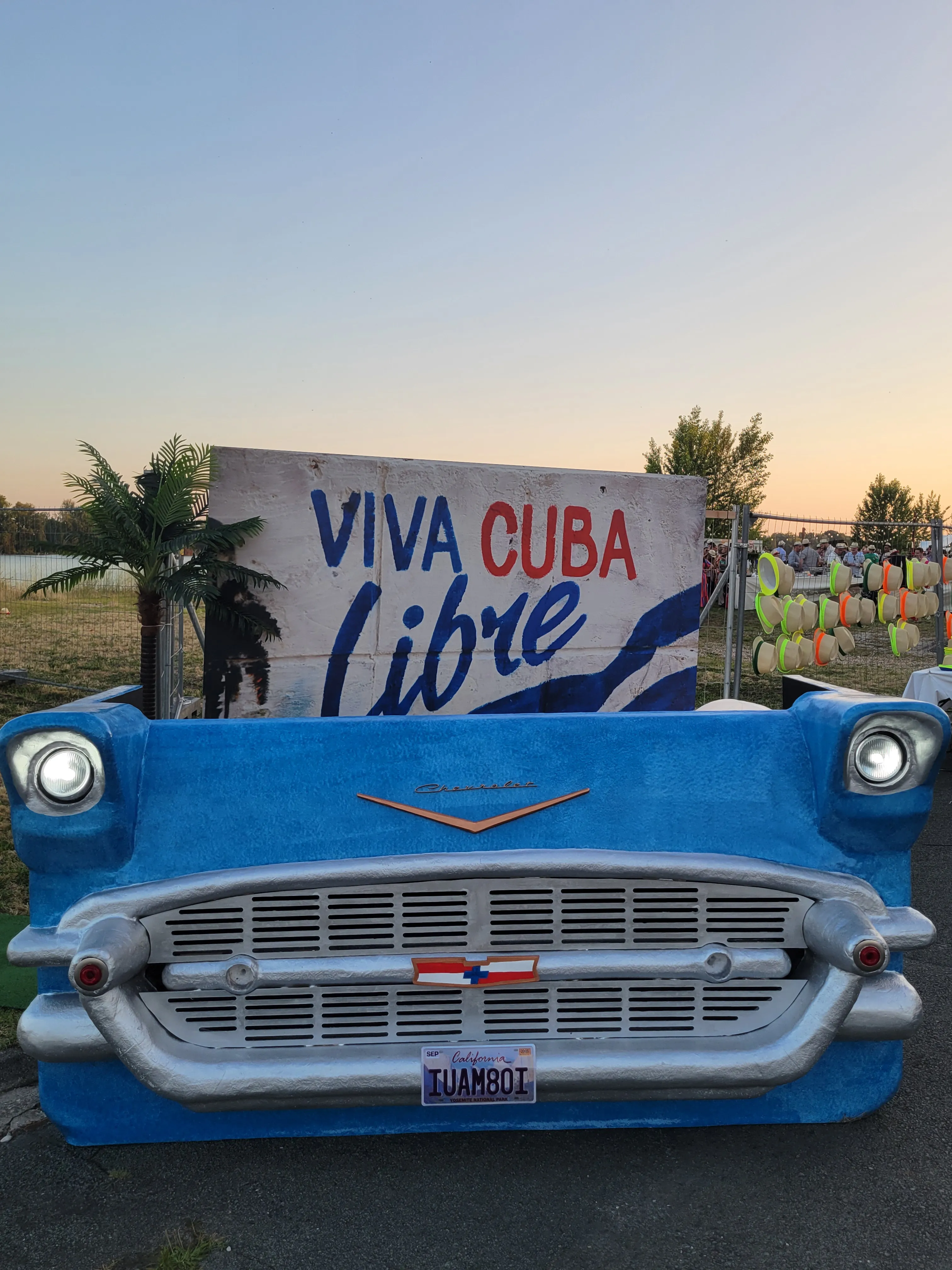 Avant d'une voiture américaine vintage bleue devant une grande bannière "Viva Cuba Libre".