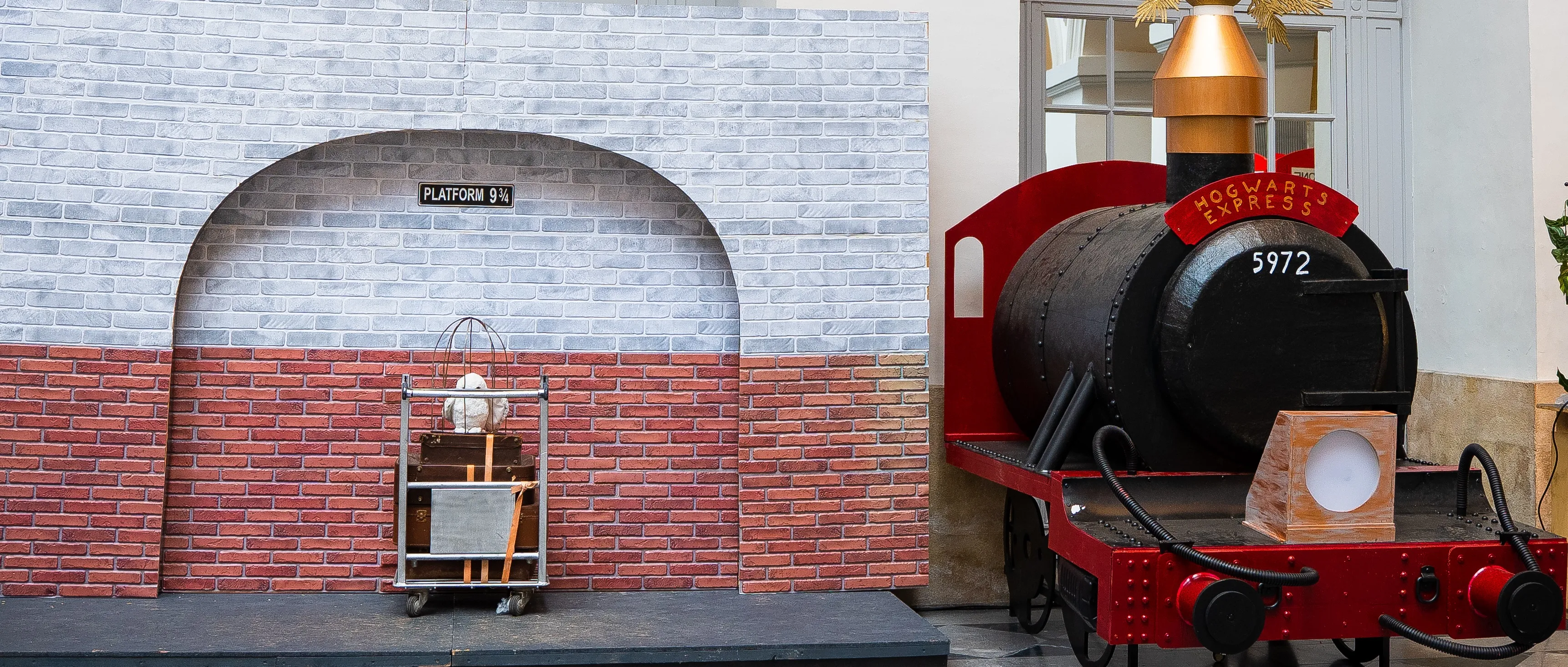 Décor de locomotive à vapeur rouge sur un quai en briques avec un panneau 9 3/4.