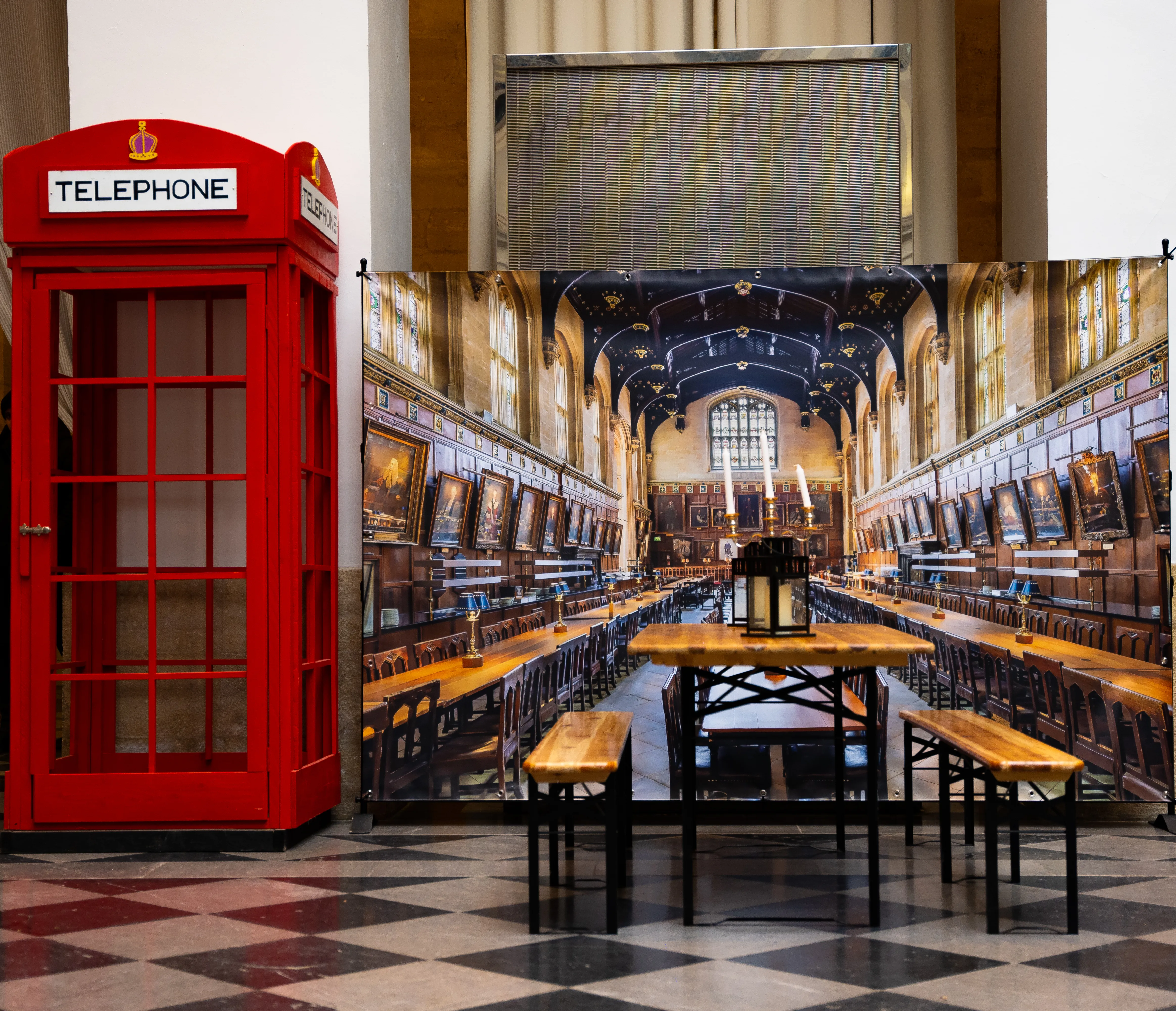 Salle de banquet style Poudlard avec une cabine téléphonique rouge anglaise installée comme élément de décor.