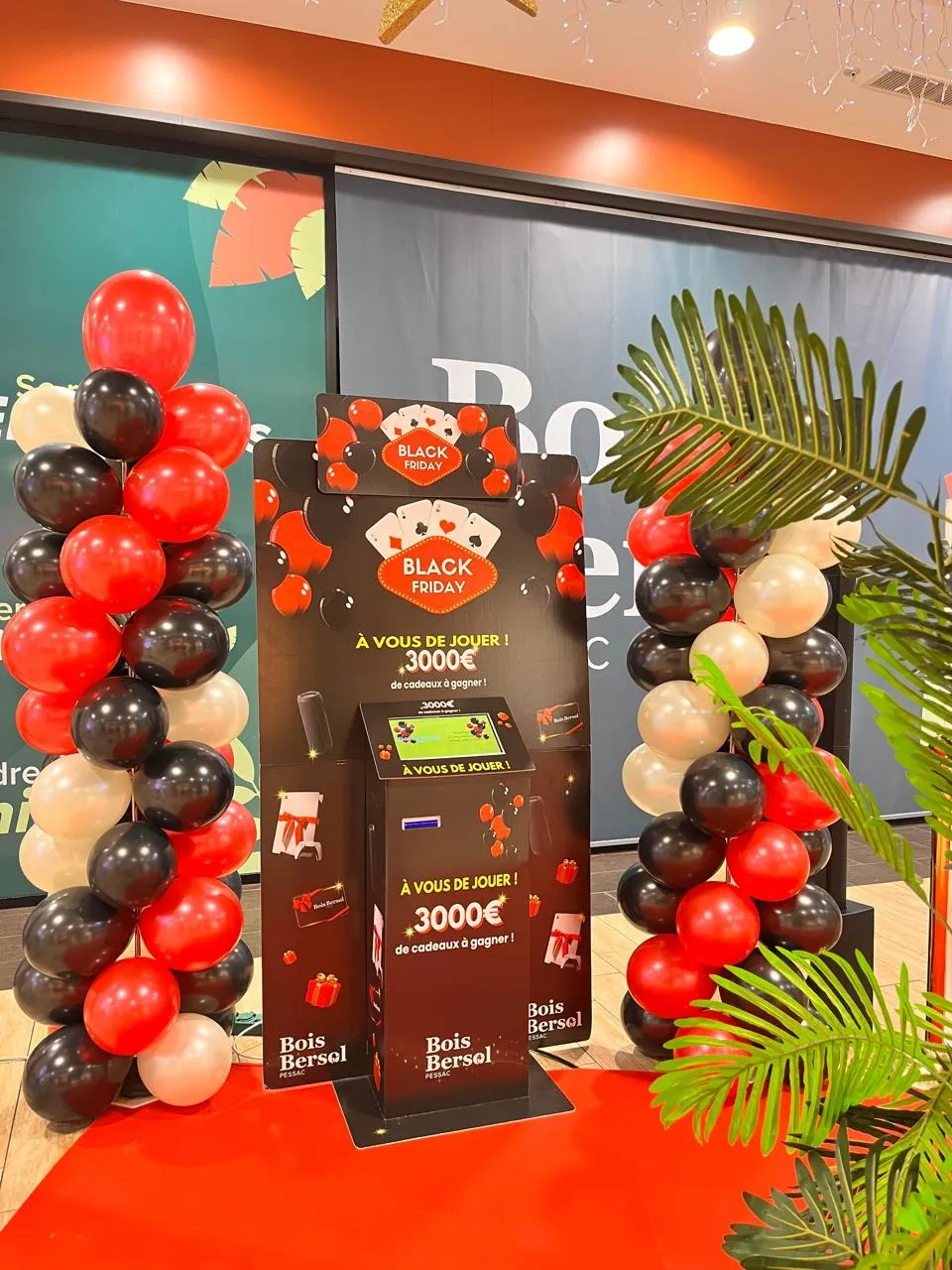 Stand d'animation pour le Black Friday entouré d'une arche de ballons rouges et noirs.