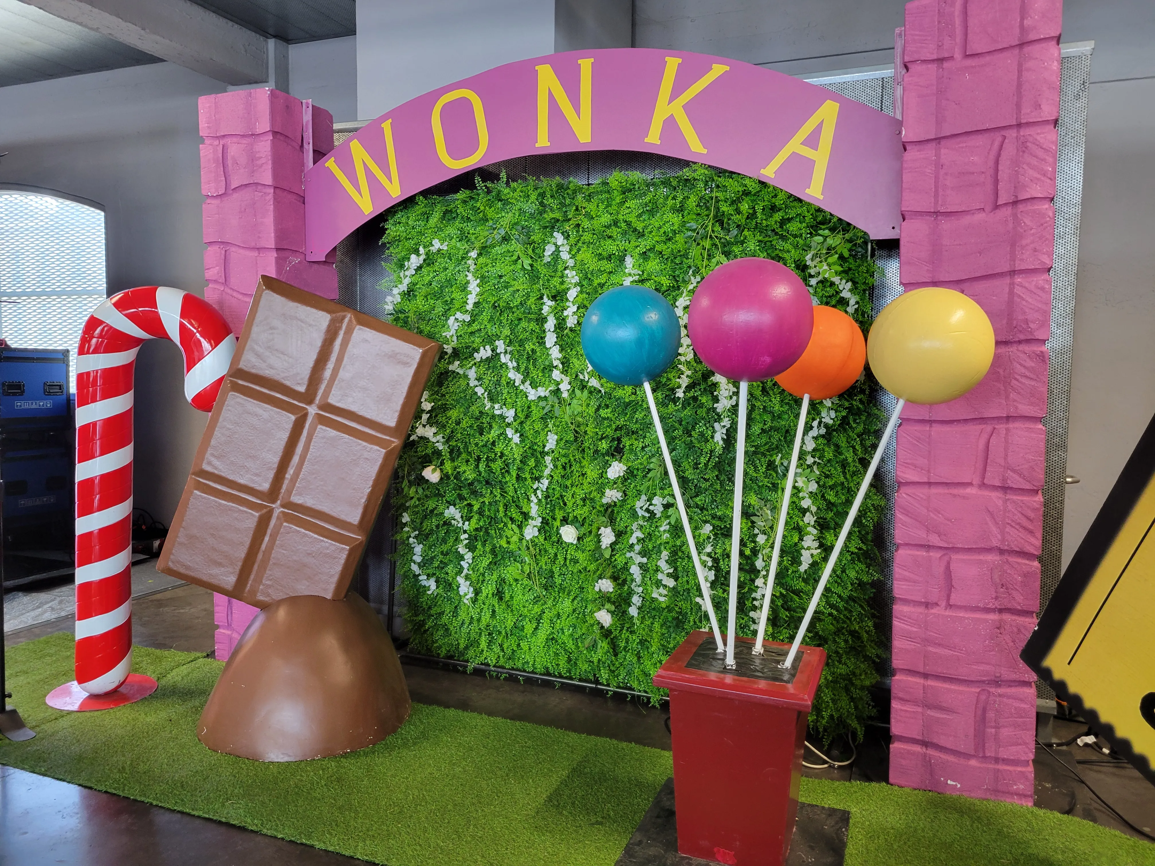 Décoration sur le thème de Wonka avec une arche, une tablette de chocolat géante et des ballons.