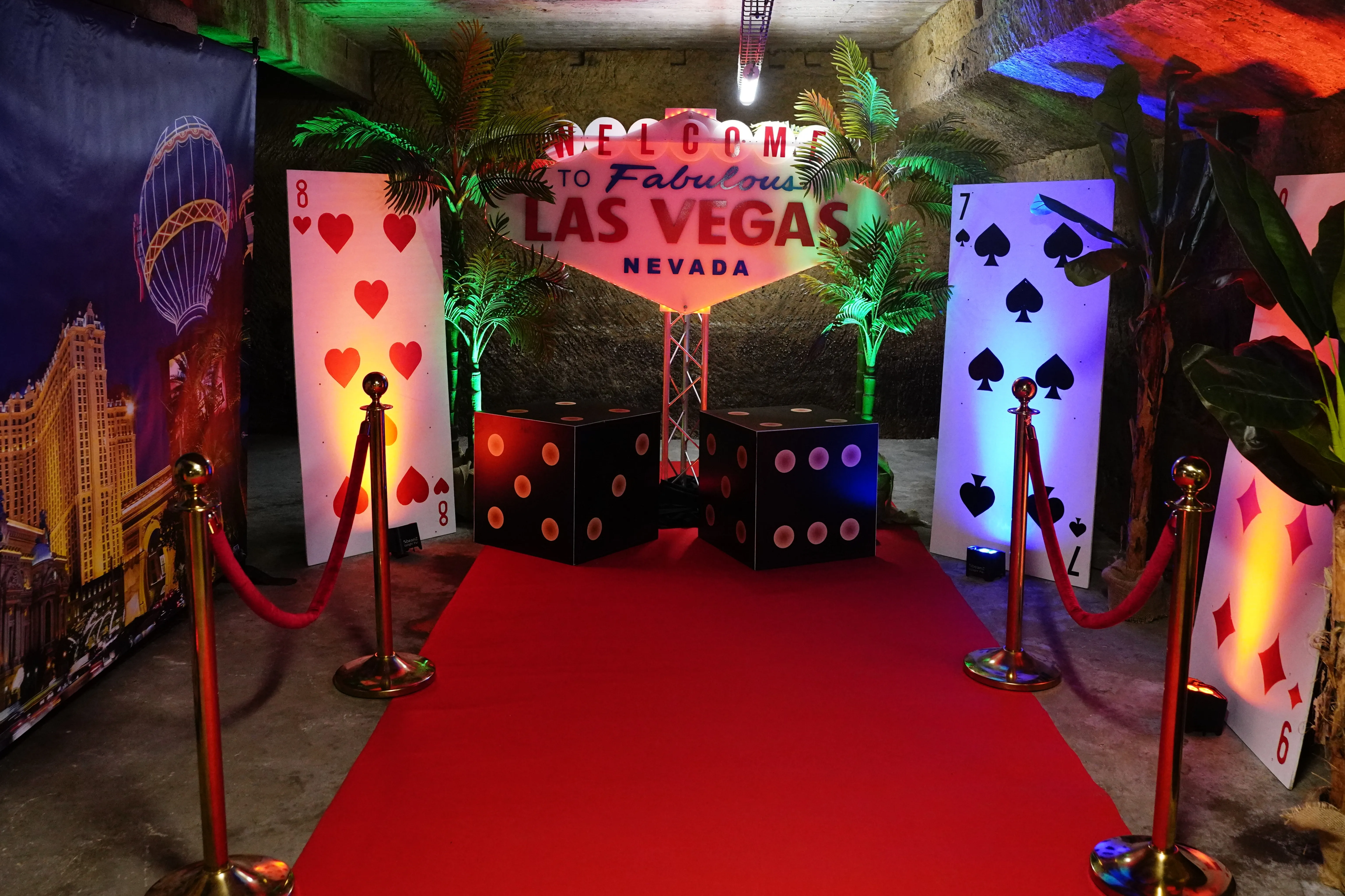 Entrée d'un événement sur le thème du casino avec un tapis rouge, des dés et des cartes à jouer géants.