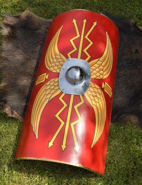 Bouclier romain décoratif rouge et or type scutum, utilisé comme élément de scénographie événementielle à thème Antiquité.