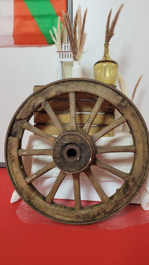 Roue de charrette ancienne en bois utilisée comme élément de décoration pour scénographie rustique, champêtre ou western