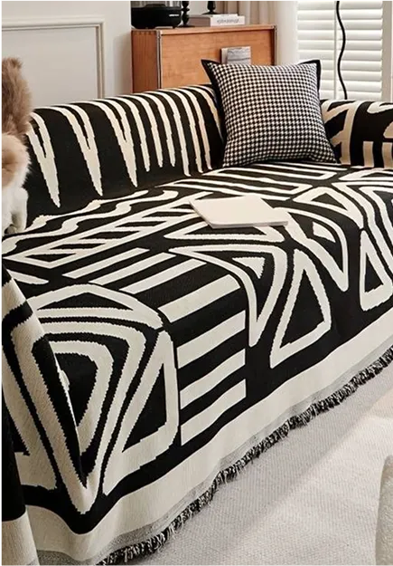 Black and white geometric patterned sofa cover with a houndstooth pillow and a book on the sofa.