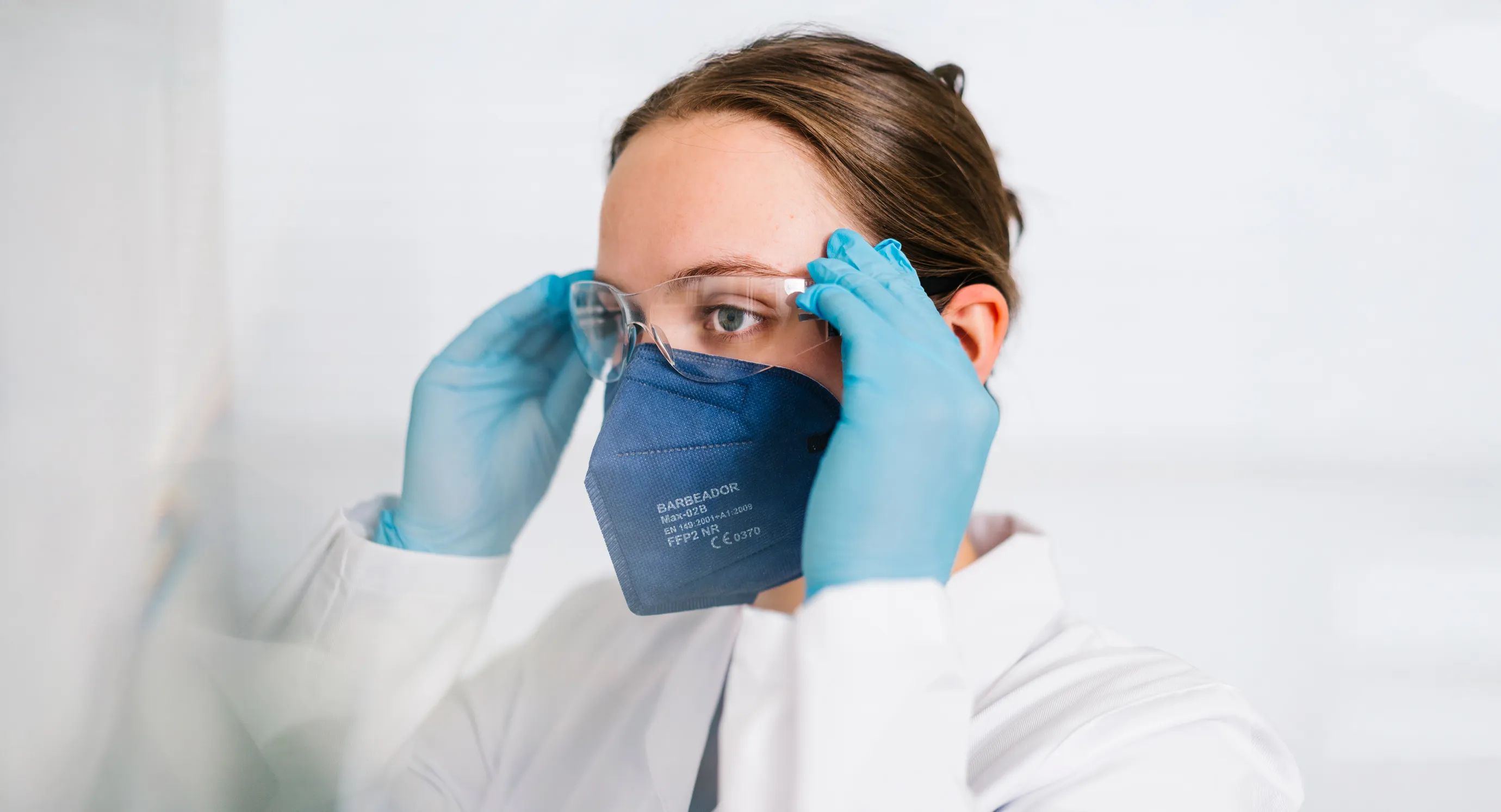 PTA der Grapengießer Apotheke trägt Schutzbrille, FFP2-Maske und Handschuhe bei der Arbeit im Labor – Symbol für Sorgfalt, Hygiene und das engagierte Team der Apotheke.