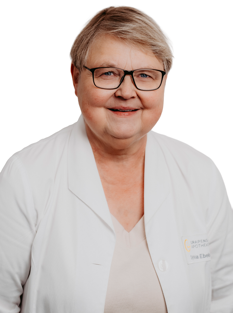 Porträt von Sylvia Ebeling, erfahrene Pharmazeutisch-technische Assistentin der Grapengießer Apotheke in Lüneburg, freundlich lächelnd im weißen Apothekenkittel.