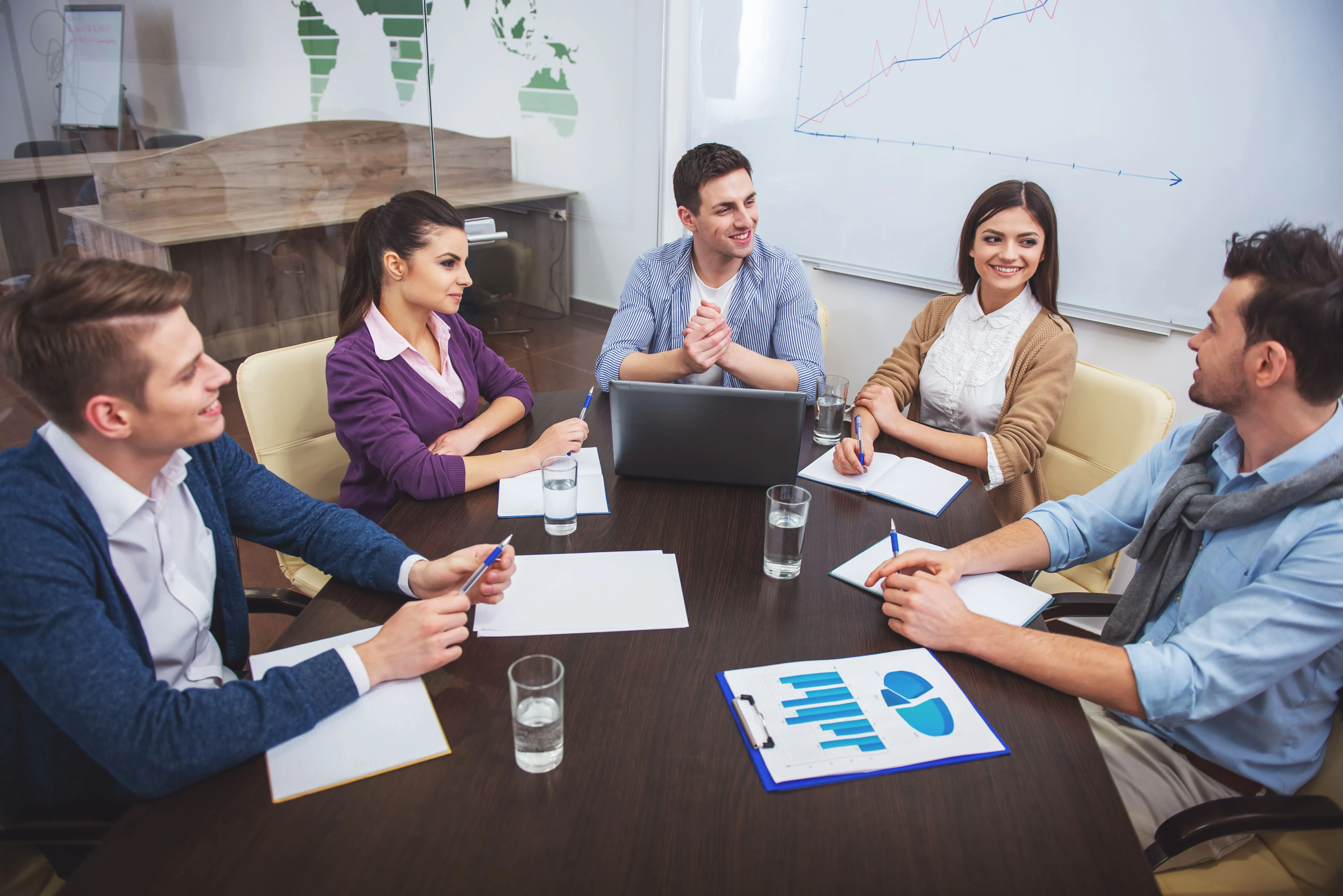 a group of co-workers sitting on a desk and talking