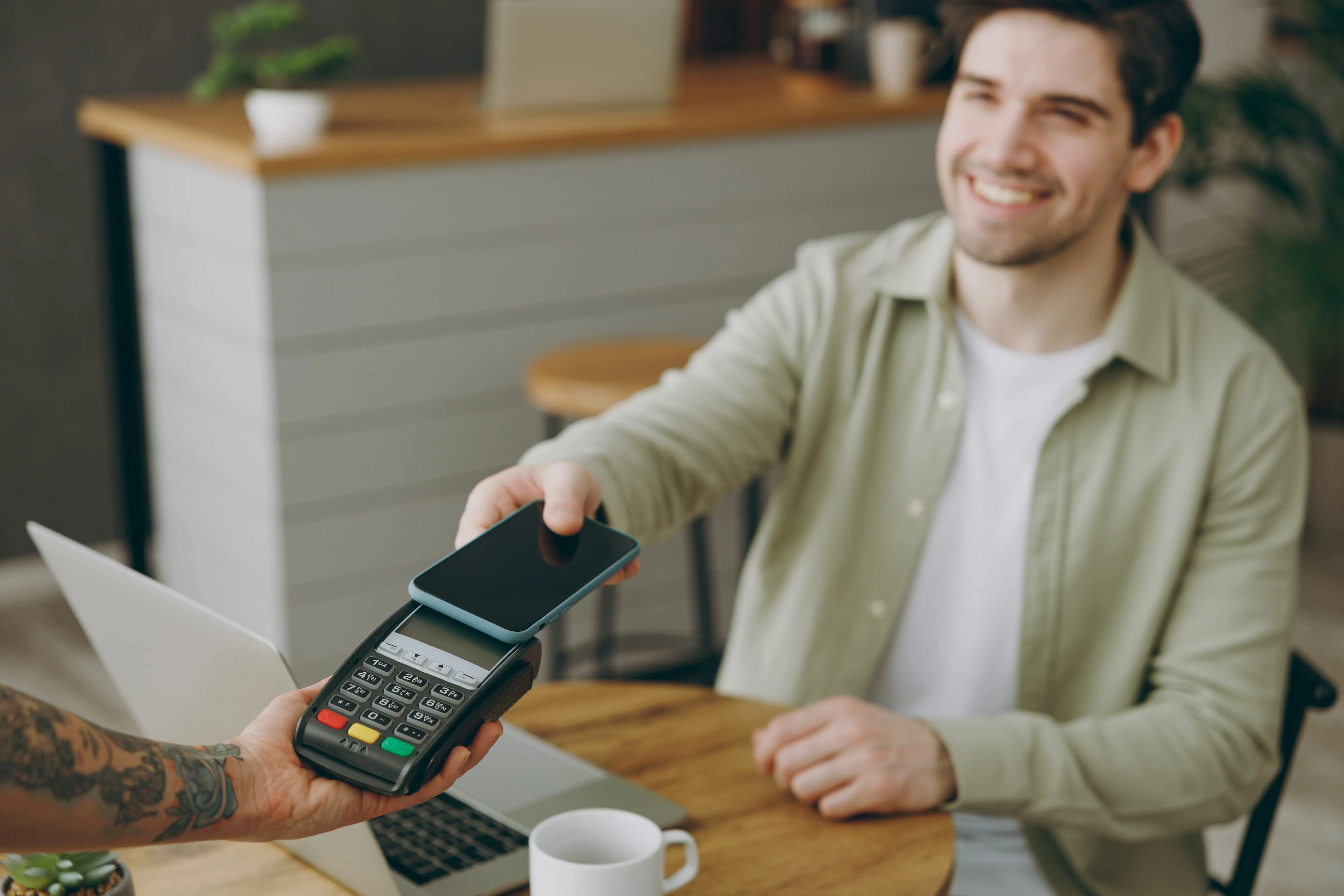 a smiling man paying with card at the coffee shop