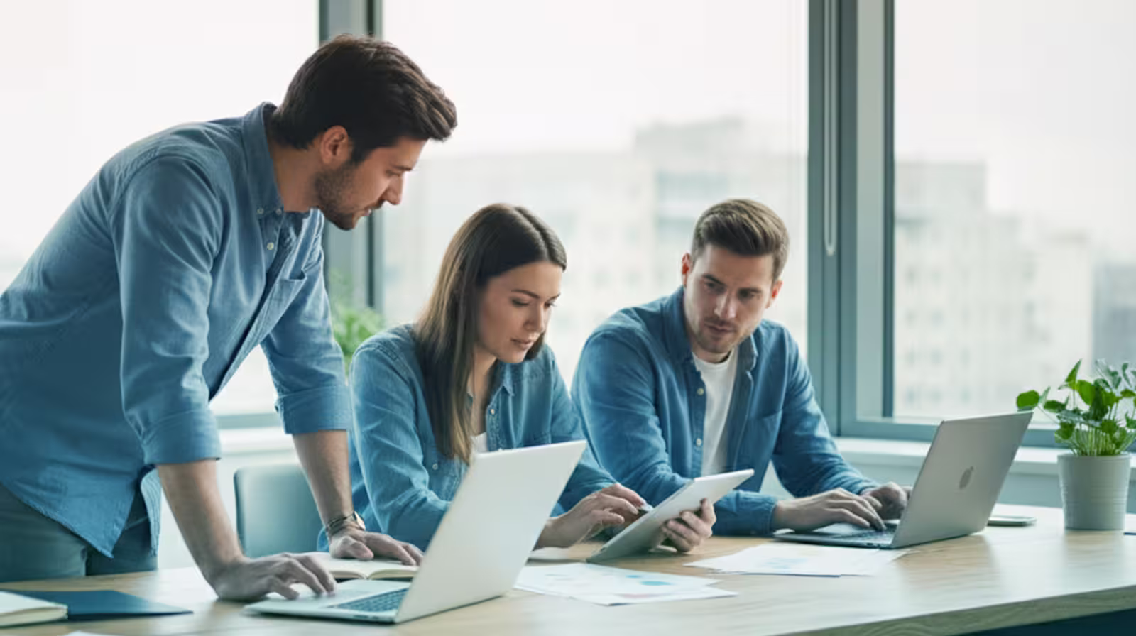 Business team collaborating on laptops and tablet in modern managed IT office