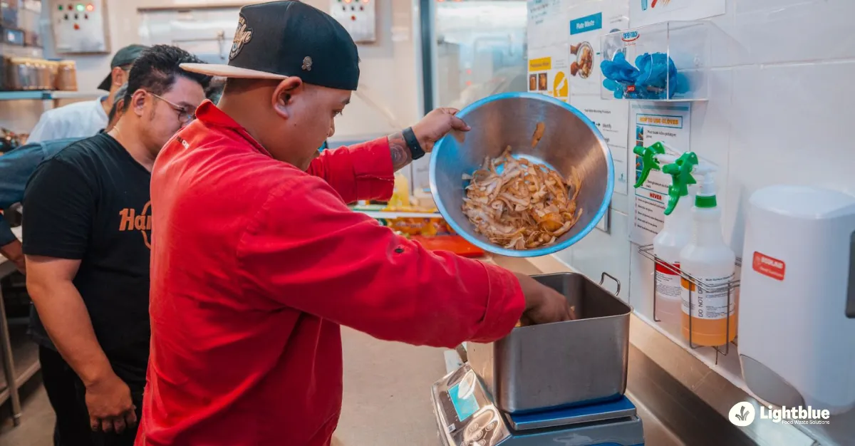 A busy commercial resort kitchen line with chefs and stewarding teams seamlessly interacting near a digital tracking station