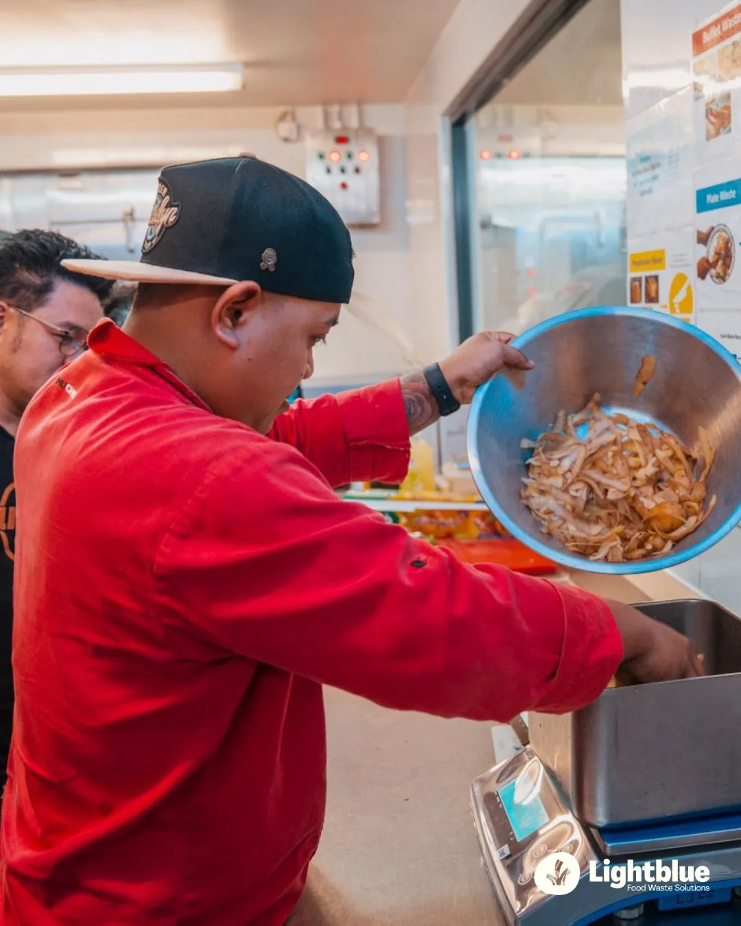 A busy commercial resort kitchen line with chefs and stewarding teams seamlessly interacting near a digital tracking station