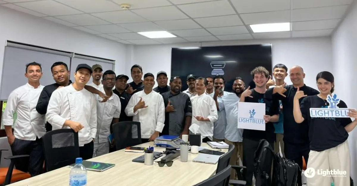 A professional group portrait of the resort executive chefs and Lightblue consultants smiling together inside a modern kitchen at CROSSROADS Maldives
