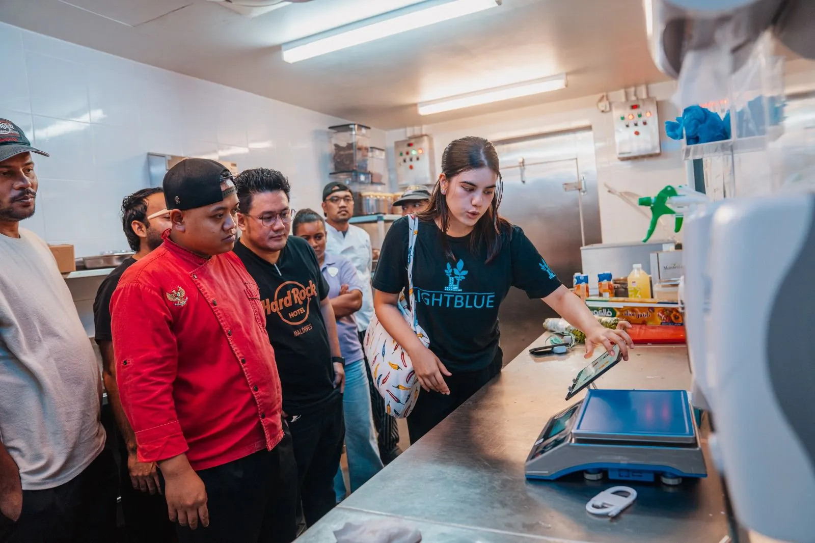Lightblue environmental consultant demonstrating the FIT digital food waste tracking scale setup at a kitchen recording point in a Maldives resort