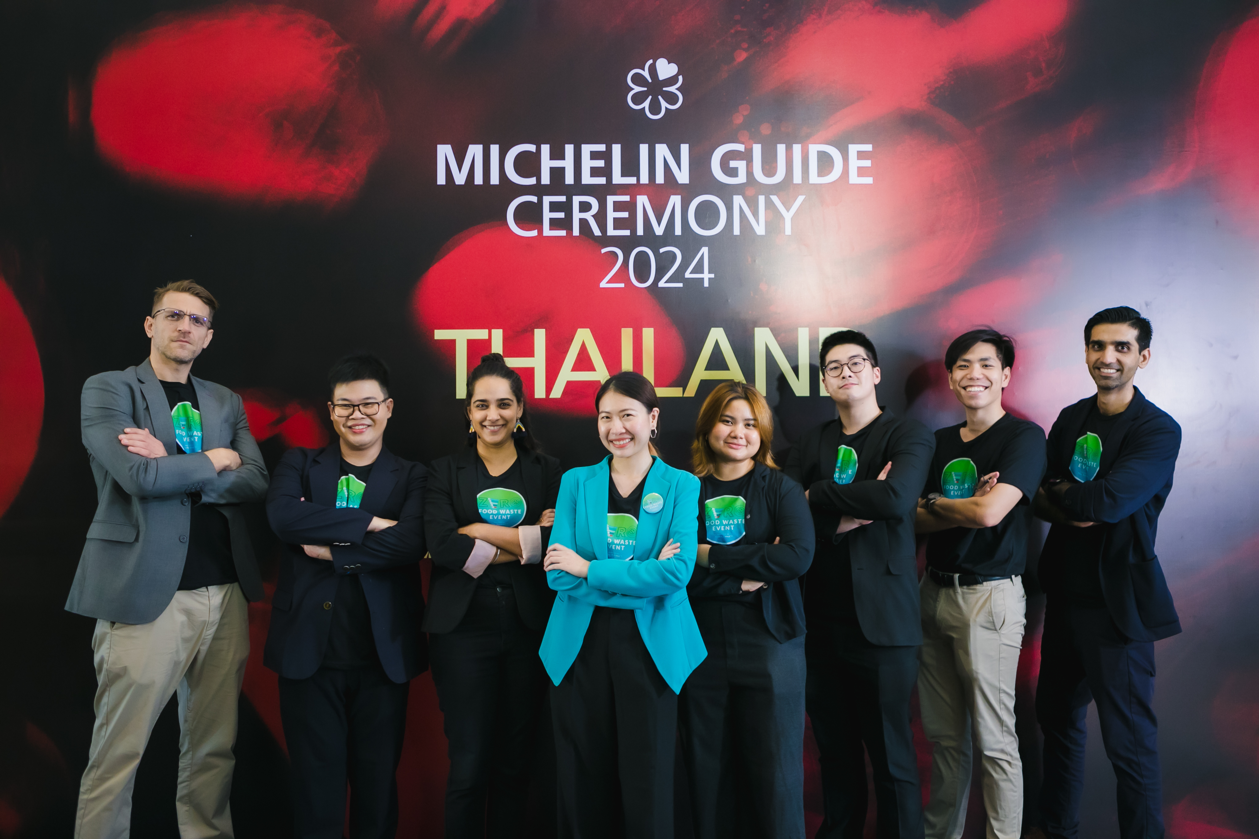 Members of the Lightblue consulting team standing together at the MICHELIN Guide Ceremony 2024, wearing matching branded "Zero Food Waste" t-shirts and smiling in front of a luxury event backdrop.
