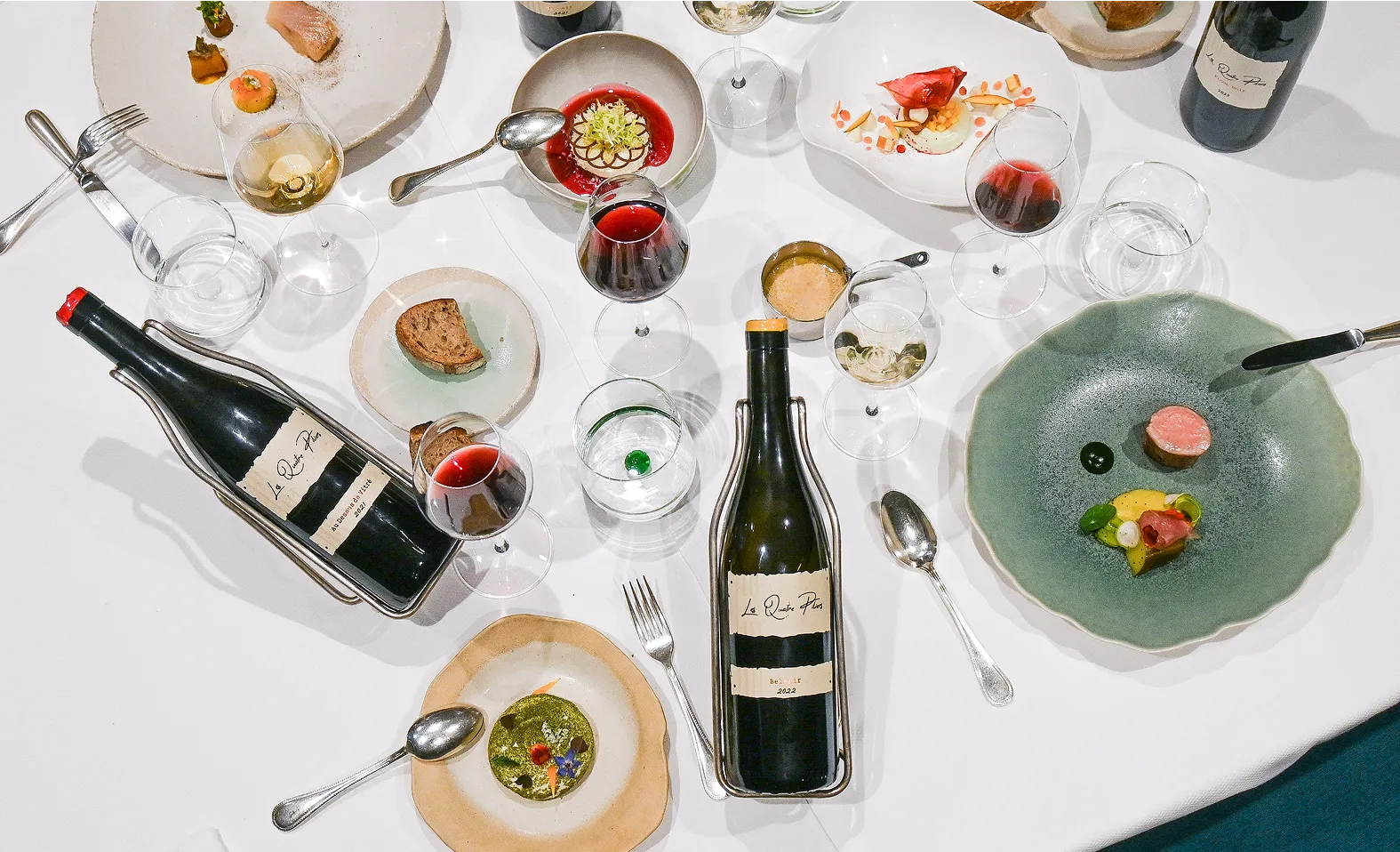A table topped with plates and bottles of wine.