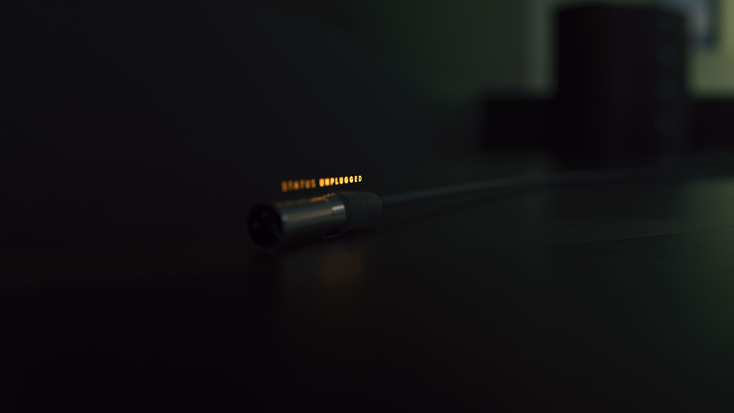 Unplugged cable lying on a dark surface with glowing text saying 'STATUS UNPLUGGED'.