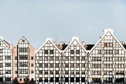 Markante Ensemble-Häuserzeile mit moderner Fachwerkarchitektur, deren streng gegliederte Fassaden in Weiß und Dunkelbraun gehalten sind und deren Giebelformen durch einheitliche Proportionen und klare Geometrie hervorstechen.