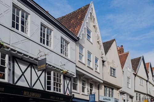 Reihung giebelständiger Altstadthäuser mit weißer Putz- und Fachwerkfassade; einheitlich proportioniert und stilistisch abgestimmt.