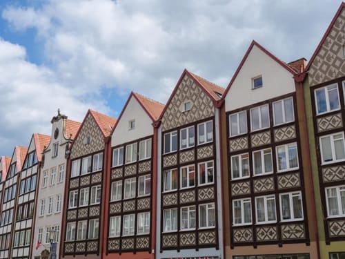 Historische Fachwerkhäuser mit verzierten Fassaden und steilen Satteldächern in geschlossener Altstadtreihe