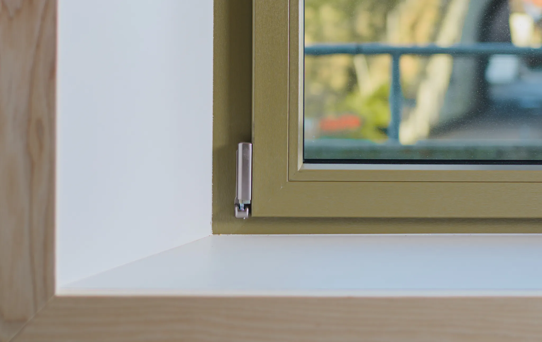 Gros plan sur un coin inférieur de fenêtre avec cadre en bois et intérieur vert, vue d'un rebord de fenêtre blanc.