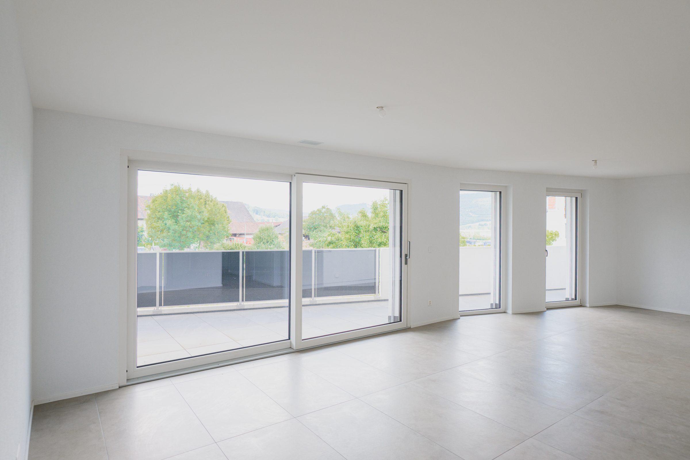Séjour lumineux avec baies coulissantes en PVC blanc de la gamme DomoPure ouvrant sur une terrasse.