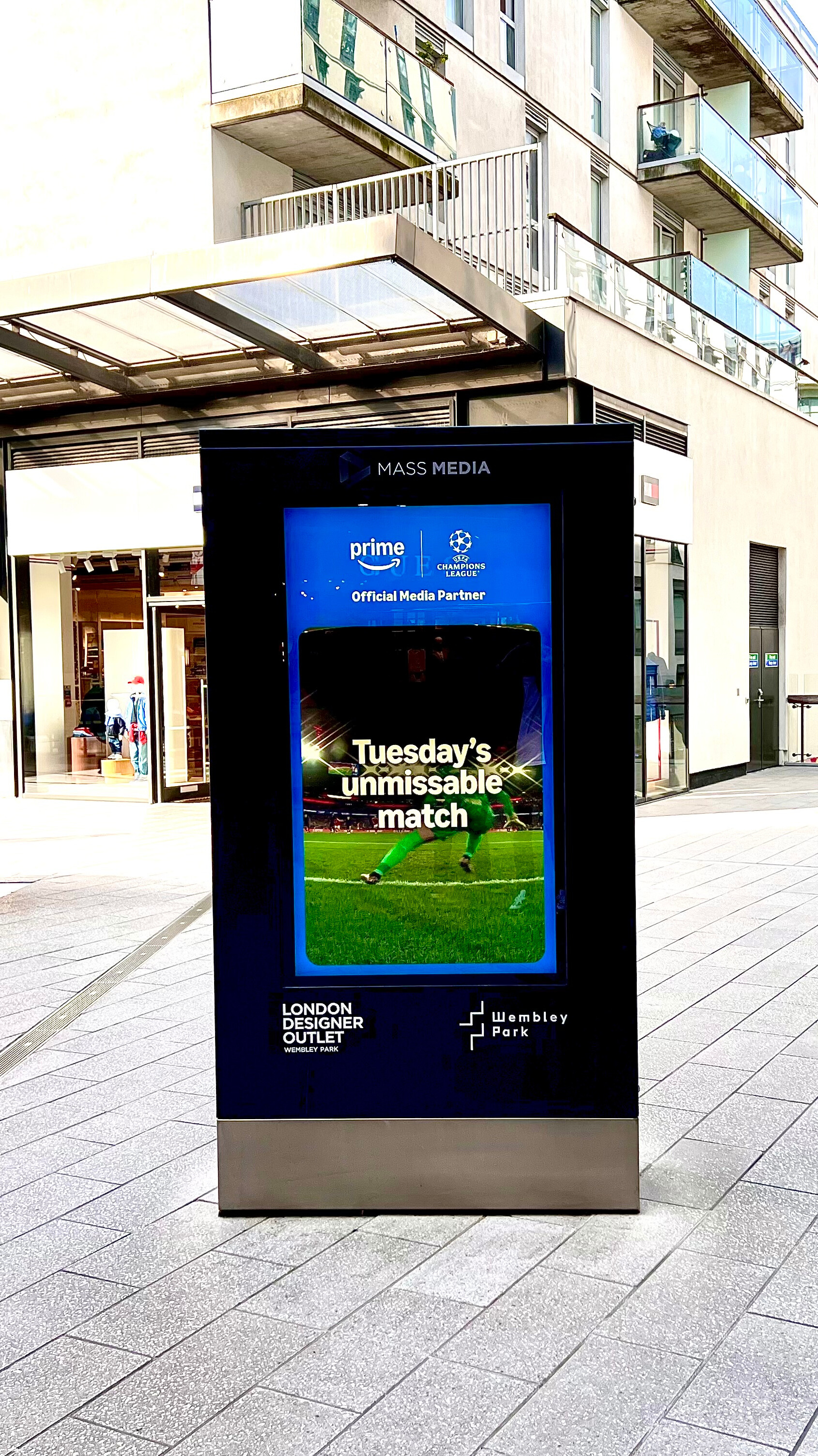 Digital billboard in an urban plaza promoting Prime Video as the official UEFA Champions League media partner with text 'Tuesday's unmissable match'.