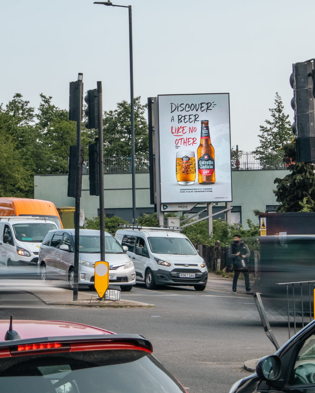Outdoor billboard advertising Estrella Galicia lager beer with the text 'Discover a beer like no other' above a bottle and a filled glass.