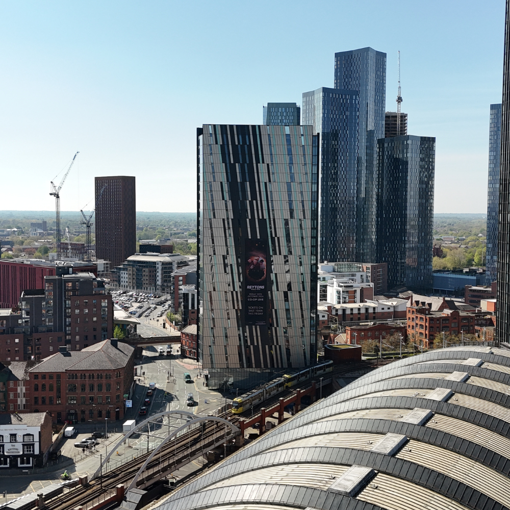 Cityscape with modern skyscrapers, train tracks, and roads under clear blue sky.