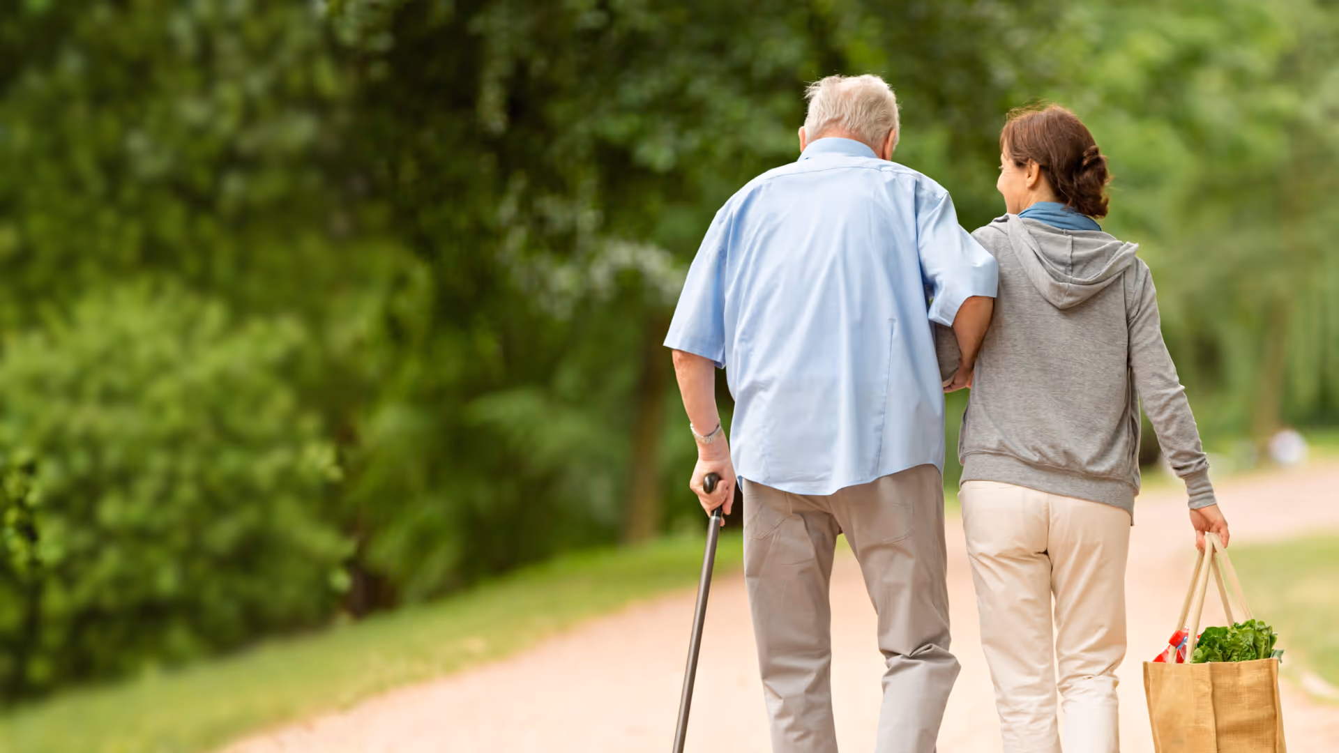 Woman helping man with wheelchair get out of brown van on a street.