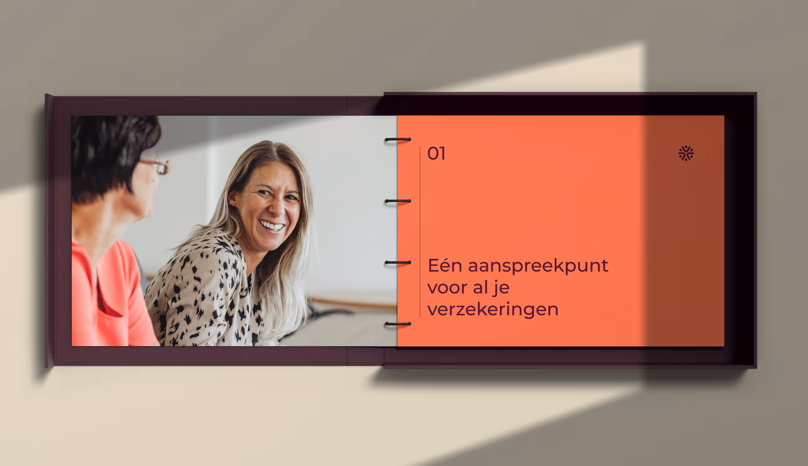 Opengeslagen brochure met links een foto van twee lachende medewerkers en rechts een oranje pagina met de titel “Eén aanspreekpunt voor al je verzekeringen.”