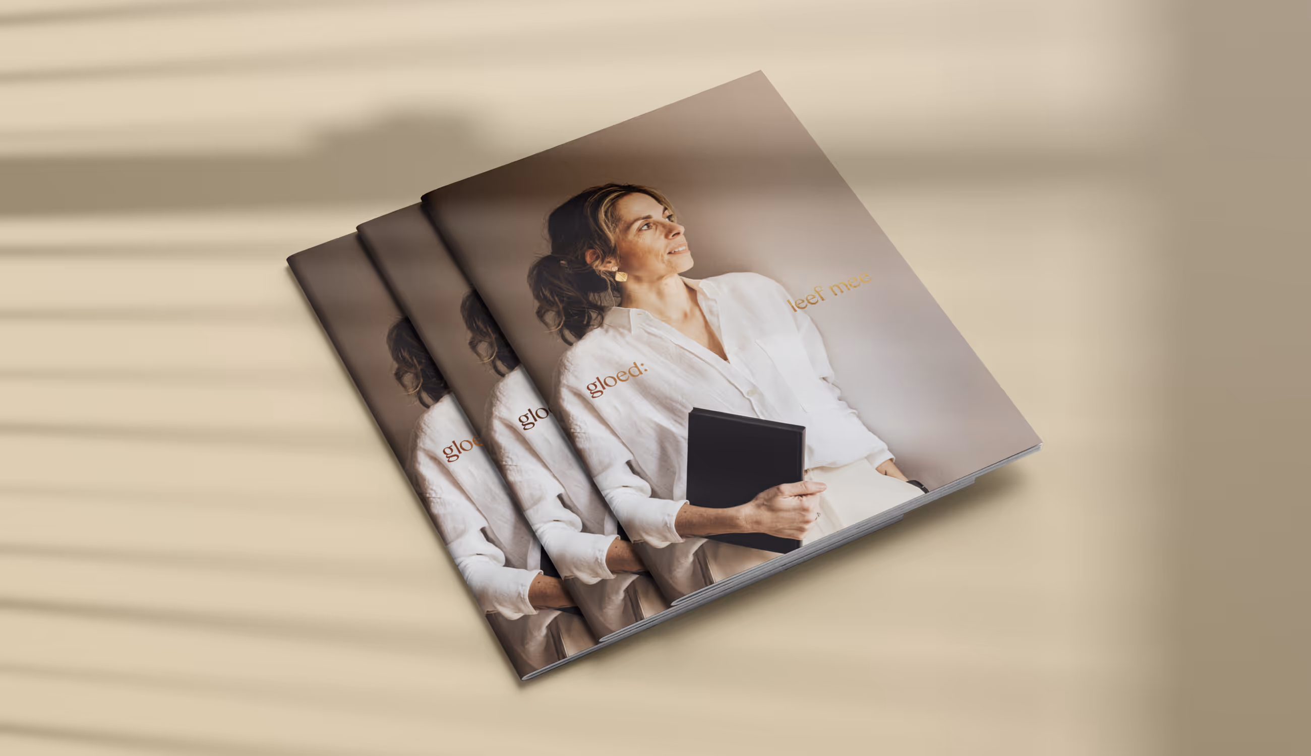 Een reeks zorgvuldig geordende brochures met het logo ‘gloed:’ op een neutrale ondergrond. De kleuren variëren van beige tot warm oranje, wat rust en consistentie uitstraalt.