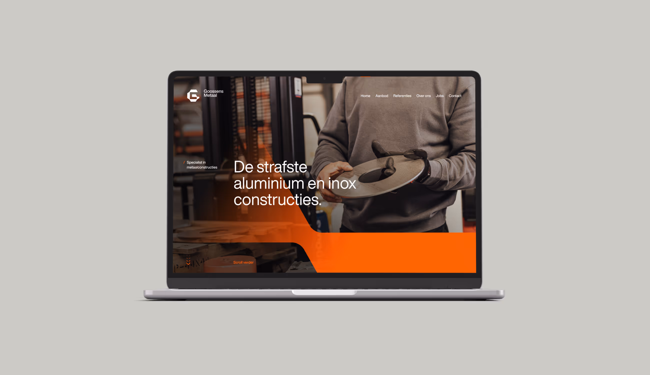 Een laptop toont de startpagina van Goossens Metaal met de tagline “De strafste aluminium en inox constructies” en een beeld van een medewerker in het atelier.