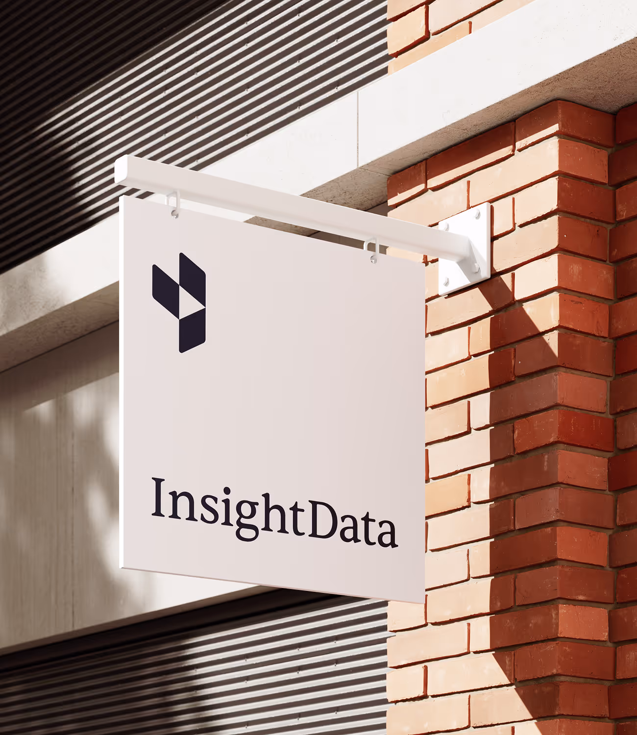 Wit uithangbord met het logo en de naam InsightData aan een bakstenen gevel. Het zonlicht werpt zachte schaduwen op de muur.