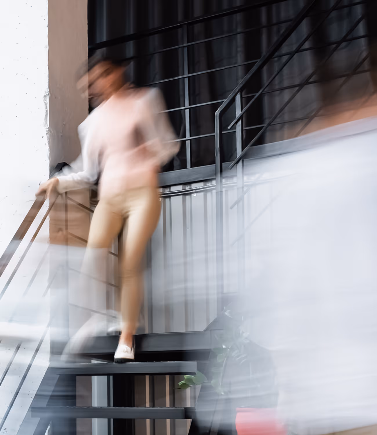 Vage foto van een persoon die een trap afloopt in een modern kantoor. De bewuste bewegingsonscherpte symboliseert snelheid en vooruitgang.